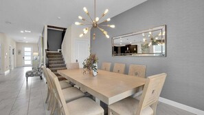 A dining room with a large table, chairs, a chandelier, and a mirror on the wall. - Ssh9044 (Davenport)