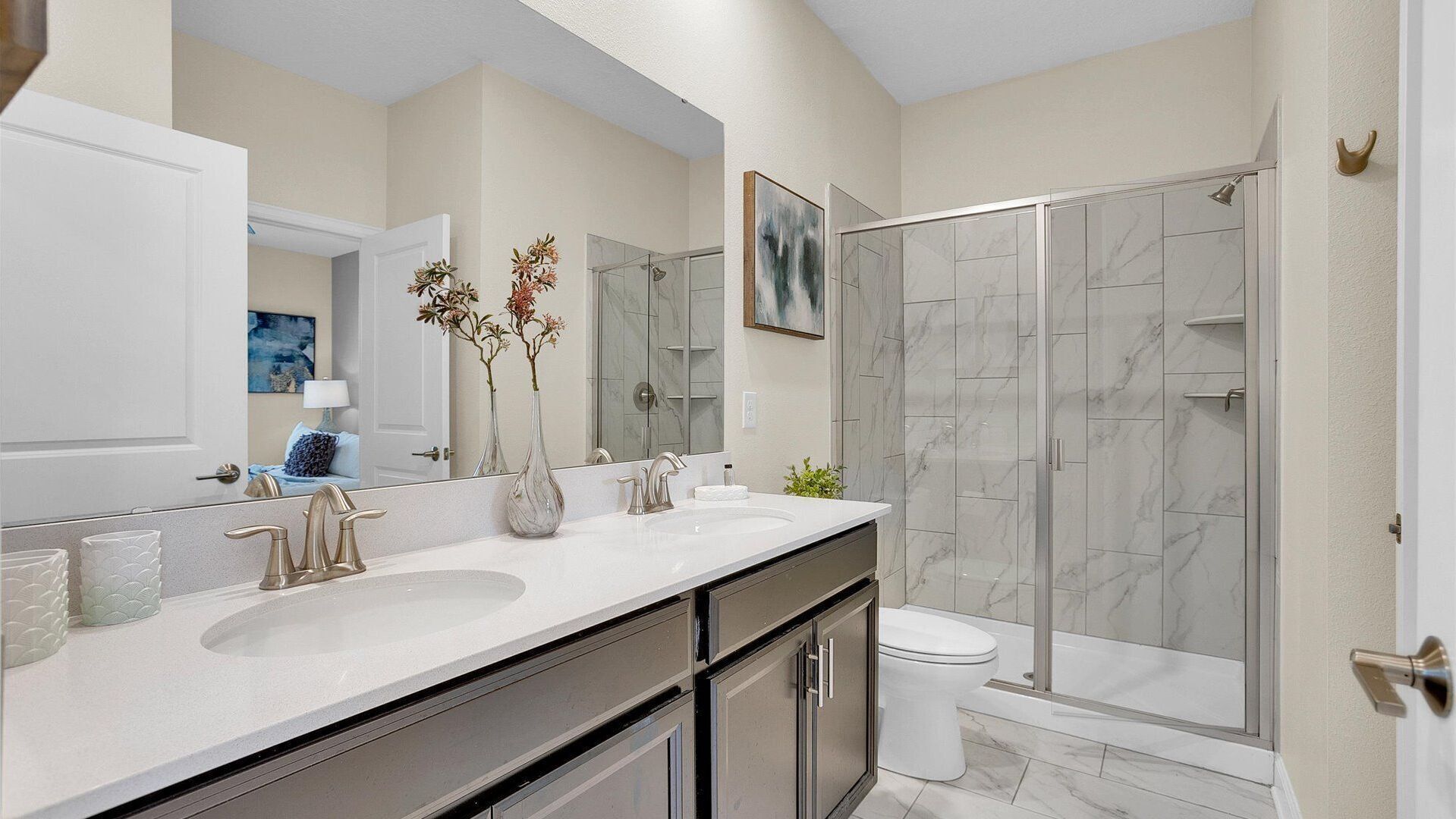 A modern bathroom with two sinks, a shower, and a toilet.