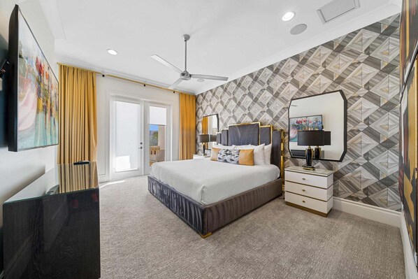A modern hotel room with a large bed, a ceiling fan, a TV, and a patterned wall. - Qj062n Imagination at Bear's Den (Kissimmee)
