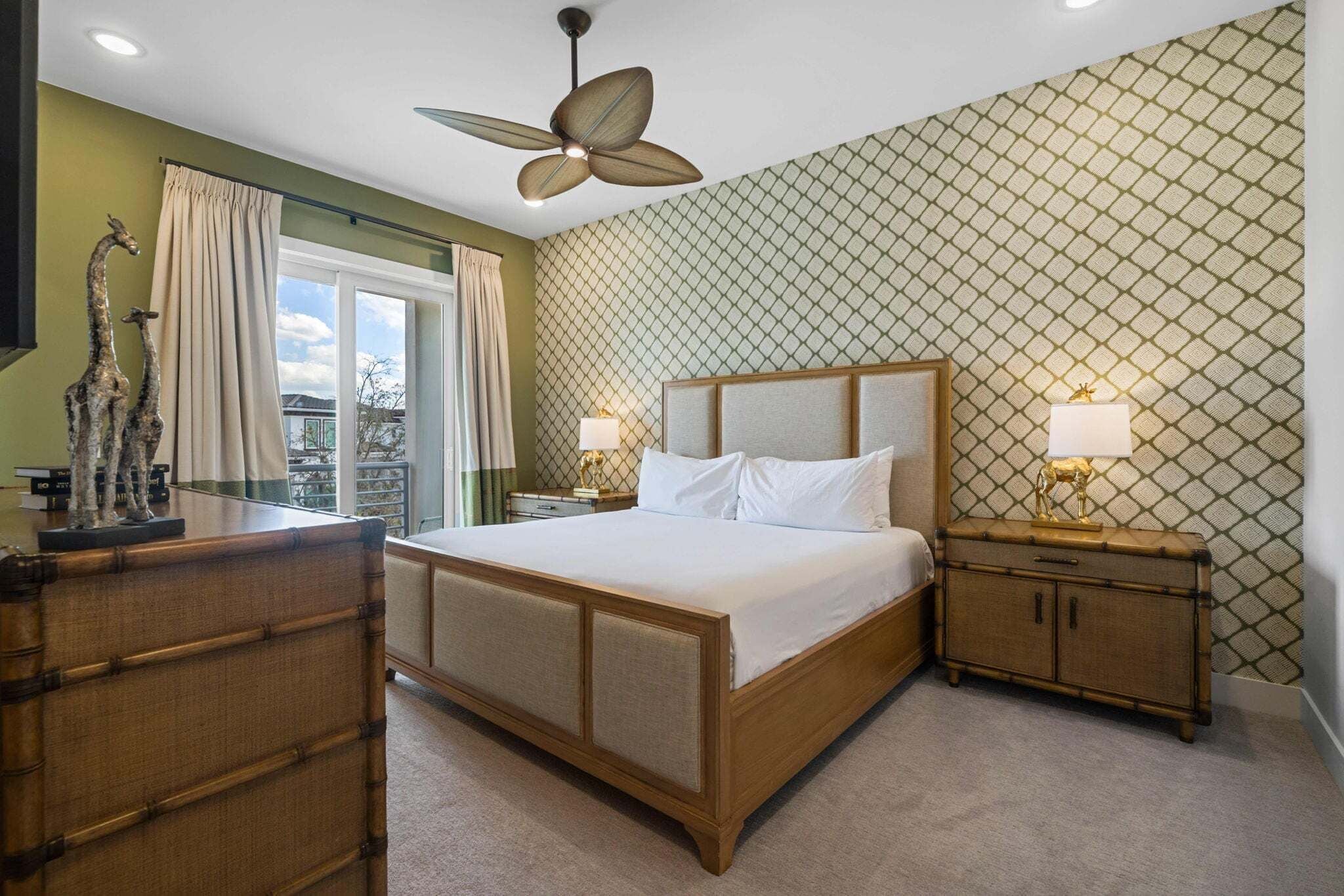 A bedroom with a bed, nightstands, a ceiling fan, and a patterned wall.