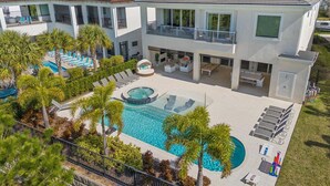 A modern two-story house with a large swimming pool, sun loungers, and a covered seating area. - Qj068n Enchantment at Bear's Den (Kissimmee)
