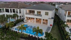 A modern two-story house with a swimming pool, outdoor seating, and a view of the neighborhood. - Qj068n Enchantment at Bear's Den (Kissimmee)