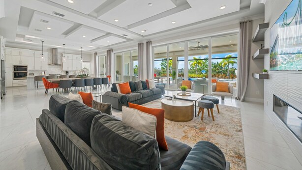 A spacious living area with a modern sofa set, a coffee table, and a dining area with a large window offering a view of the outdoors. - Qj068n Enchantment at Bear's Den (Kissimmee)
