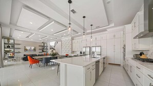 A spacious kitchen with white cabinetry, a large island, and pendant lighting. - Qj068n Enchantment at Bear's Den (Kissimmee)