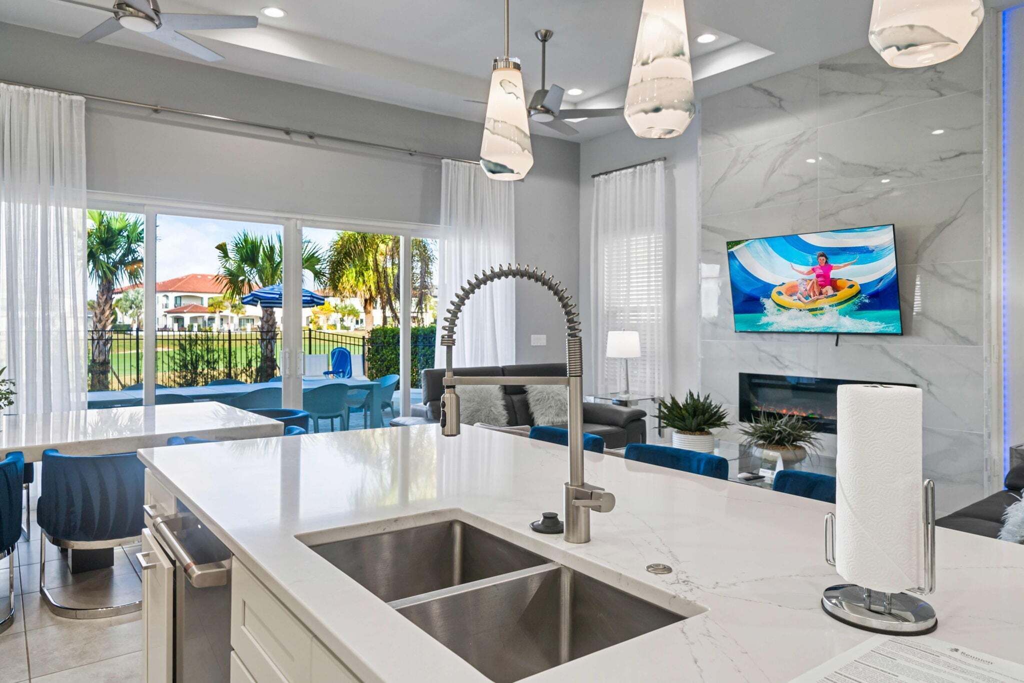 Una cocina moderna con una isla grande, un lavaplatos integrado y un televisor de pantalla plana montado en la pared.