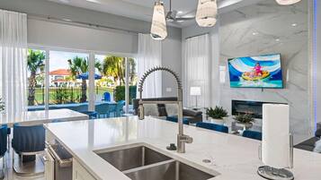 Una cocina moderna con una isla grande, un lavaplatos integrado y un televisor de pantalla plana montado en la pared.