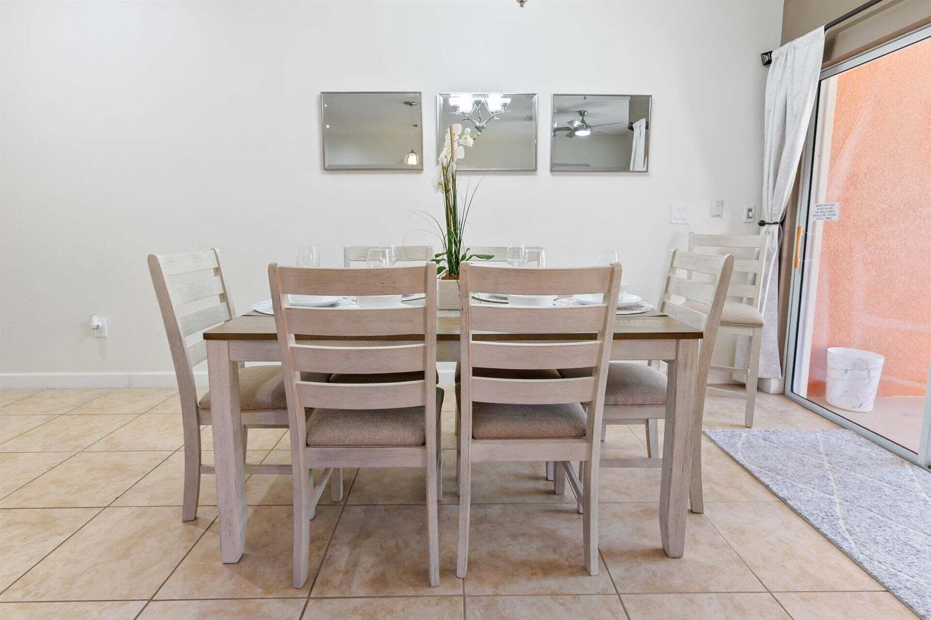 Een eetruimte met een tafel, stoelen, een potplant en een glazen schuifdeur.
