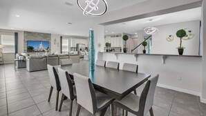 Une cuisine moderne avec des meubles blancs, un îlot central et un coin repas comprenant une grande table et des chaises.