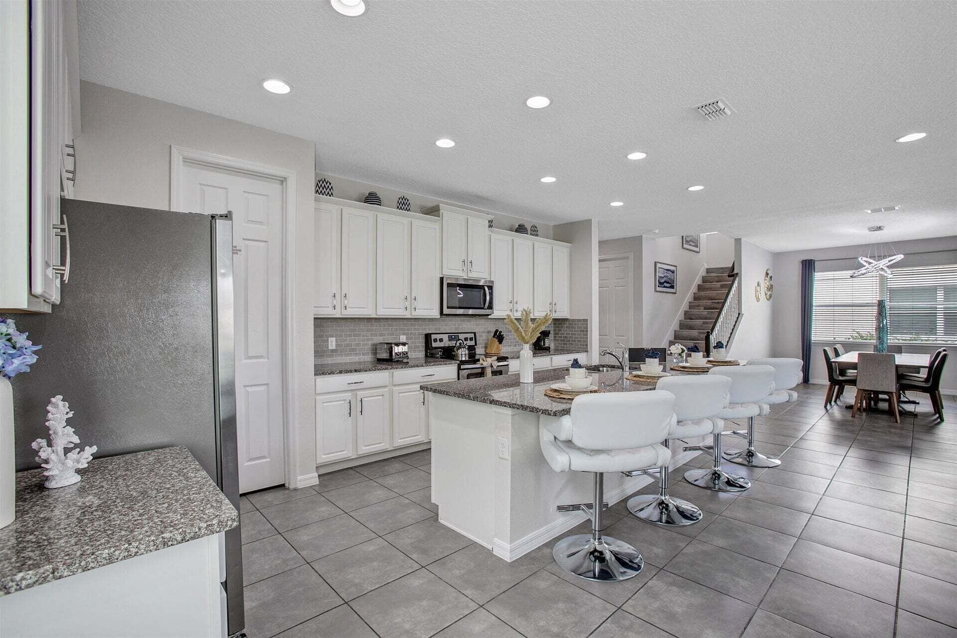 A modern kitchen with white cabinets, granite countertops, and a central island with bar stools.