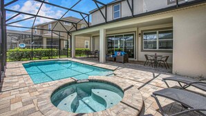 Une piscine extérieure couverte, dotée d’un jacuzzi, de mobilier de jardin et offrant une vue sur les maisons voisines.