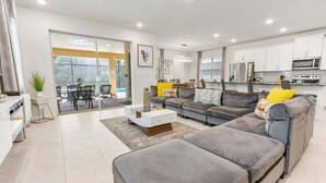 Un salon moderne avec un canapé gris, une table basse blanche et un coin repas comprenant une table et des chaises.