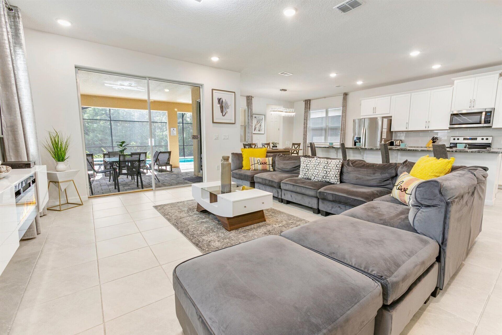 A modern living room with a grey sofa, a white coffee table, and a dining area with a table and chairs.
