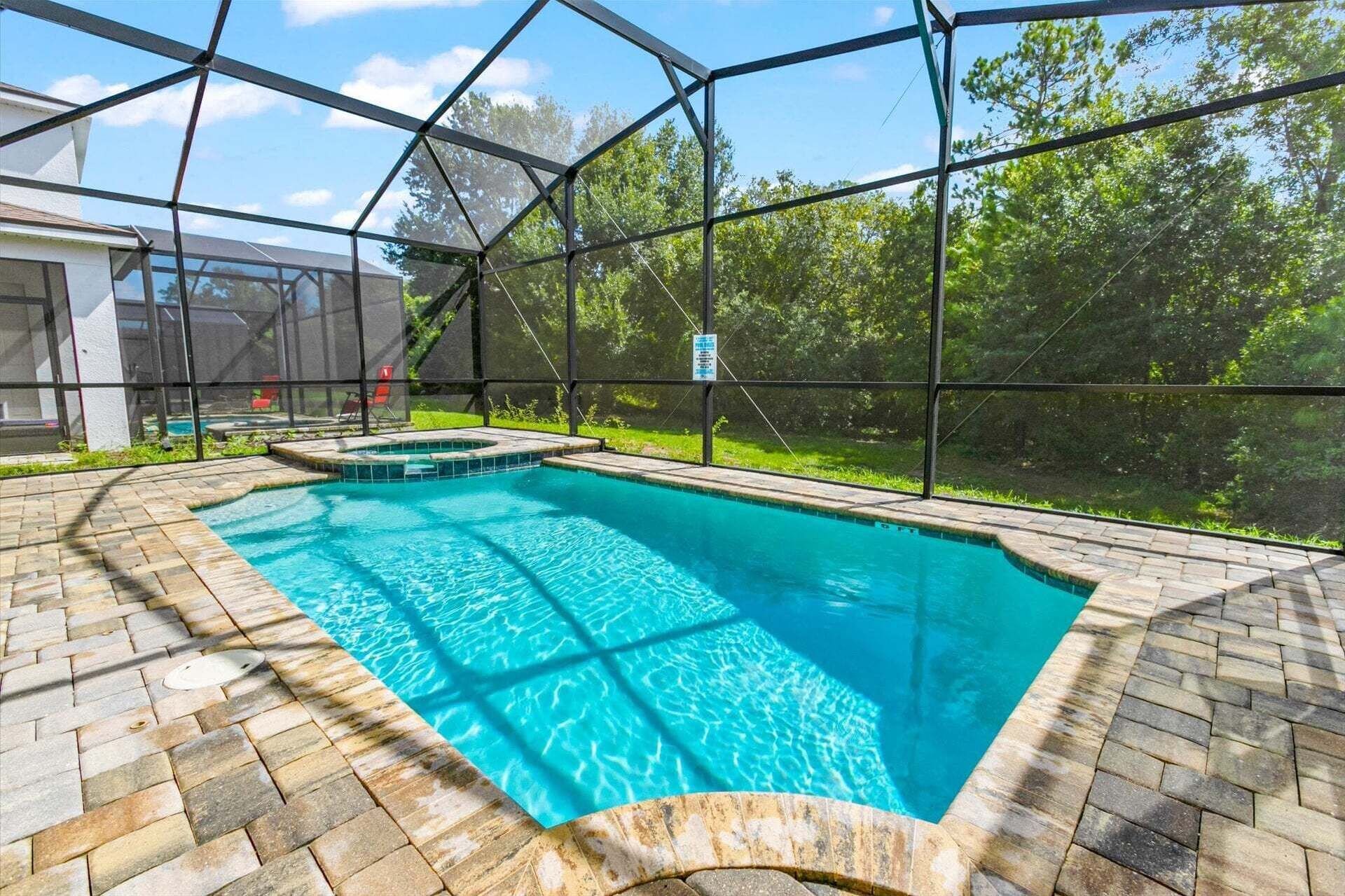 Ein Schwimmbecken mit einer Ziegelterrasse, umgeben von einer Glaskonstruktion.