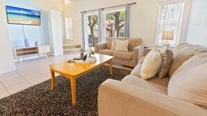 A living room with a sofa, a coffee table, and a TV on the wall. - Ccl8536 (Kissimmee)