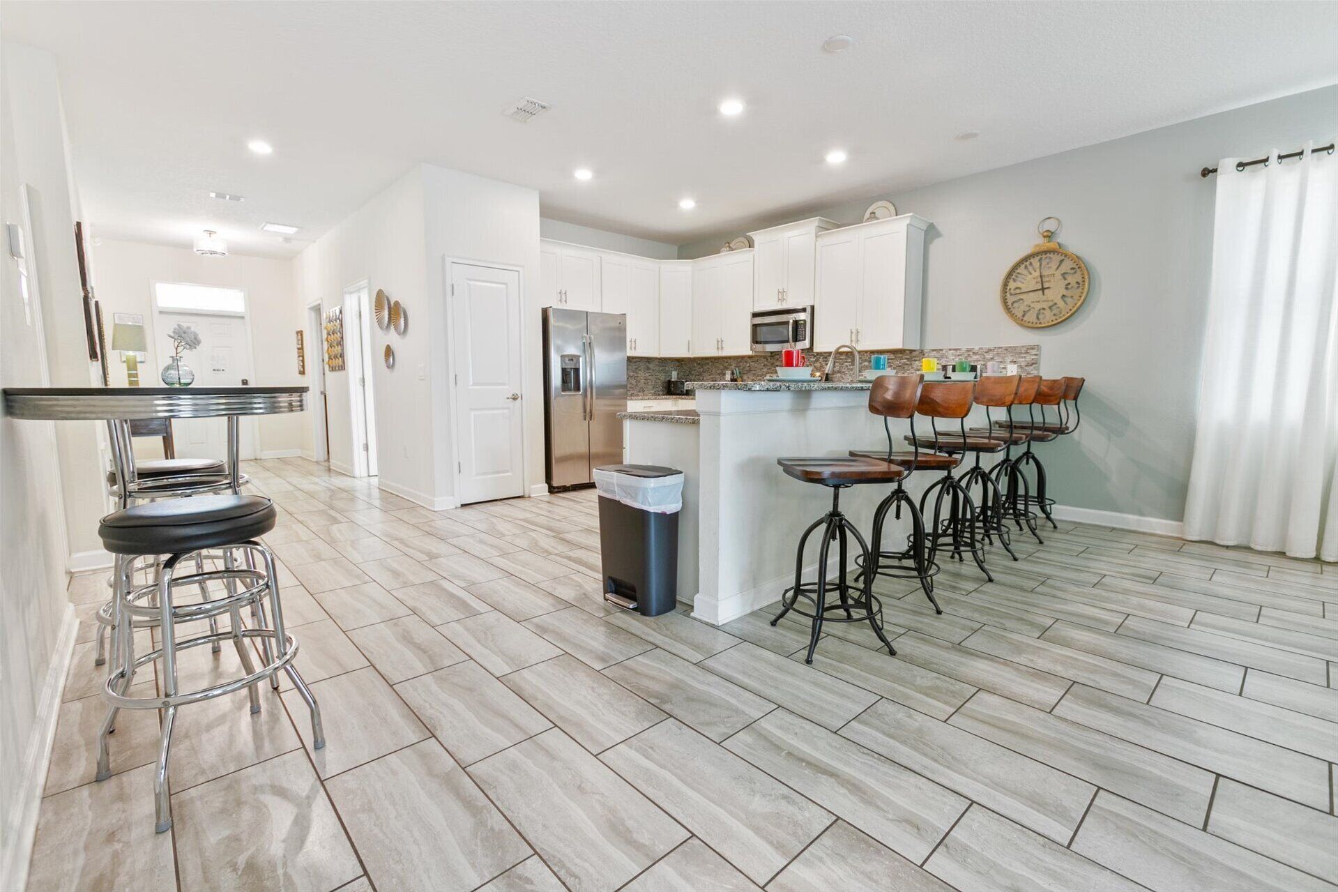 A modern kitchen with a central island, stainless steel appliances, and bar stools.