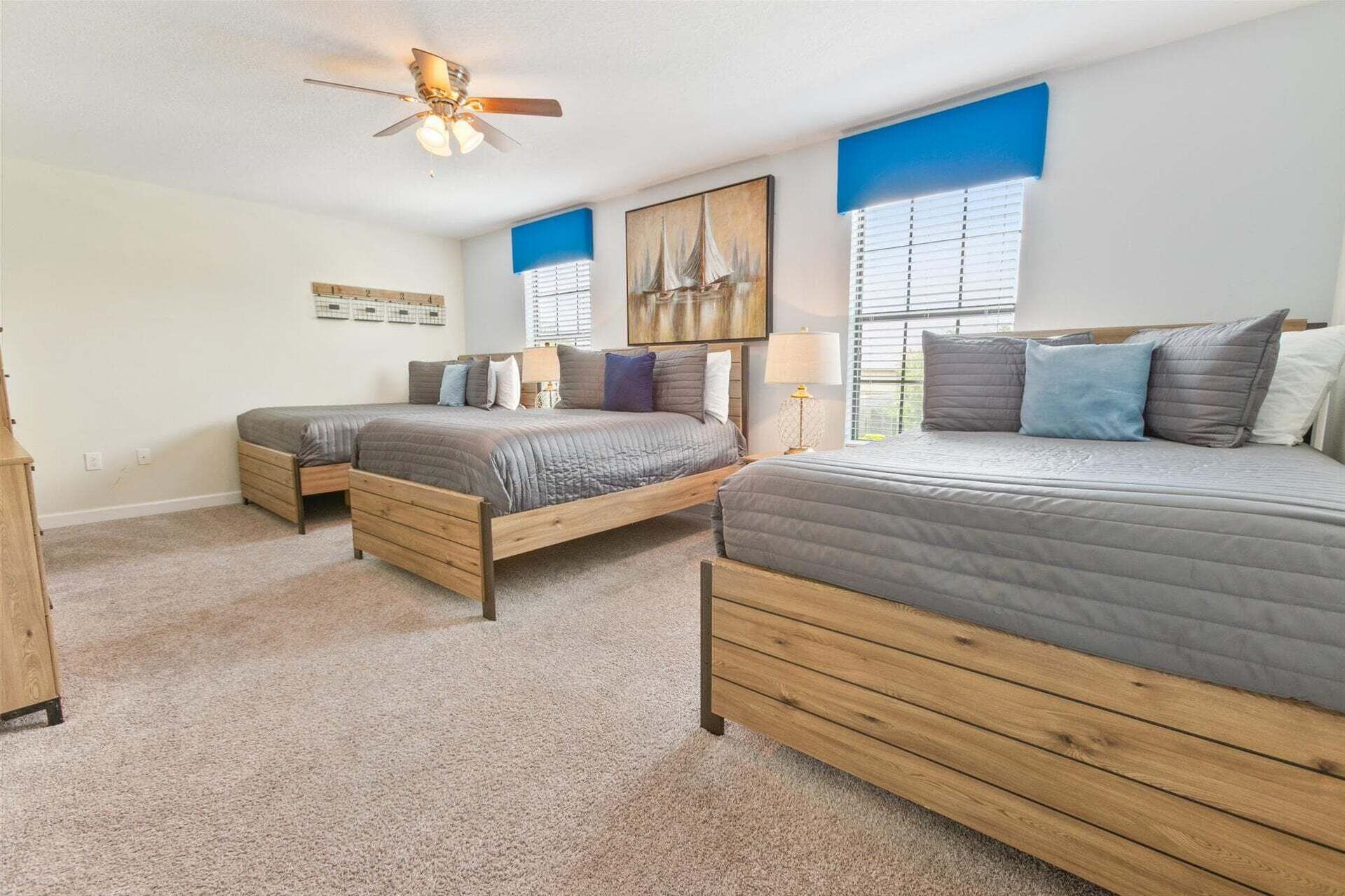 A bedroom with two beds, a ceiling fan, and a large window with blinds.