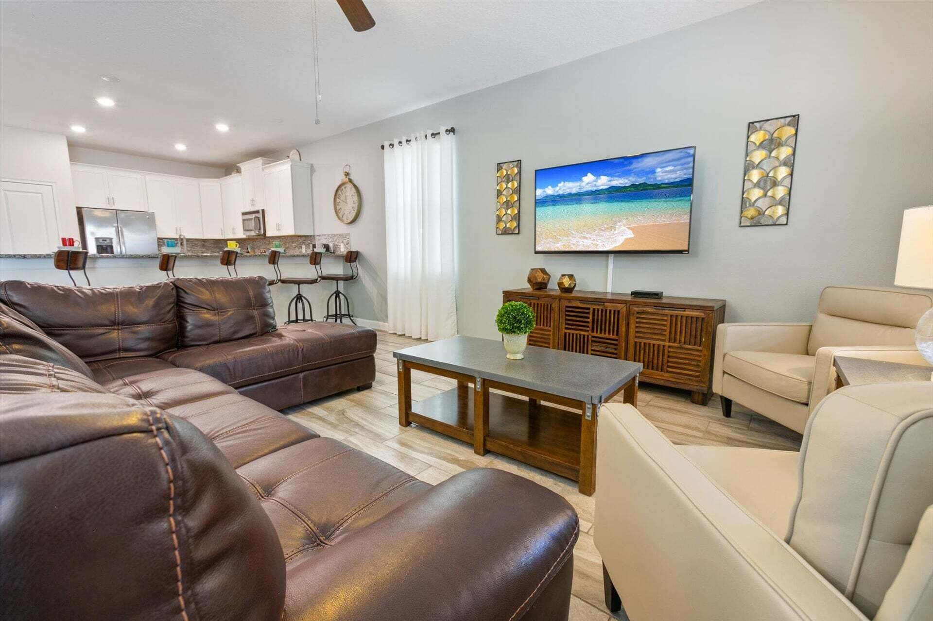 A living room with a sofa, a coffee table, and a TV displaying a beach scene.
