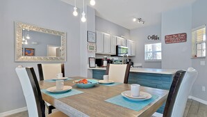 Una cocina moderna con armarios blancos, un microondas y un cartel de café.