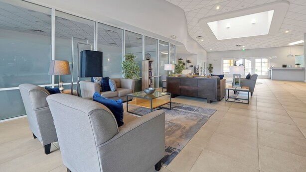 Un vestíbulo amplio con mobiliario moderno, ventanas grandes y un techo alto.