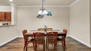 Ein Esszimmer mit Holztisch und -stühlen, einer Pendelleuchte und einem Wandbehang.