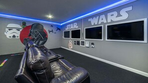 A room with a Star Wars theme, including a wall mural, a reclining chair, and multiple screens. - Hzd9057 (Davenport)