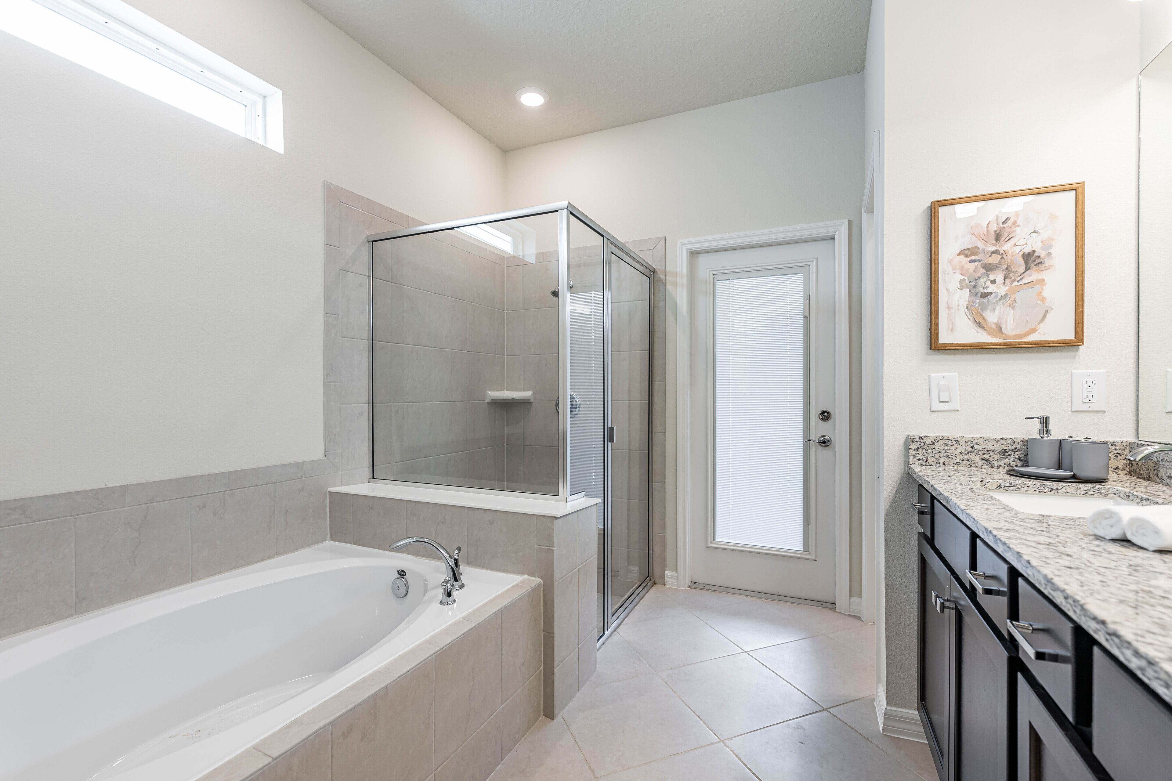 A modern bathroom with a glass-enclosed shower, a freestanding bathtub, and a marble countertop with a sink.