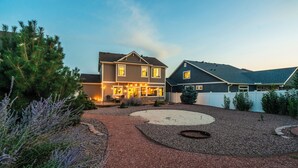 A residential area with two houses, one with a porch and string lights, and a gravel driveway with landscaping. - Spacious Family Getaway Near Downtown (Fountain)