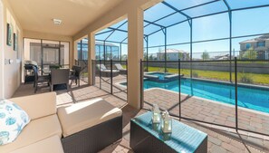 Eine sonnige Terrasse mit Pool, Sitzgelegenheiten im Freien und Blick auf benachbarte Häuser.