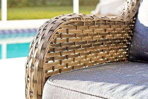 A wicker chair with a cushioned seat and backrest, positioned near a poolside area. - Tuscan Hills Home Private Pool, Game Room& Near Disney (Davenport)
