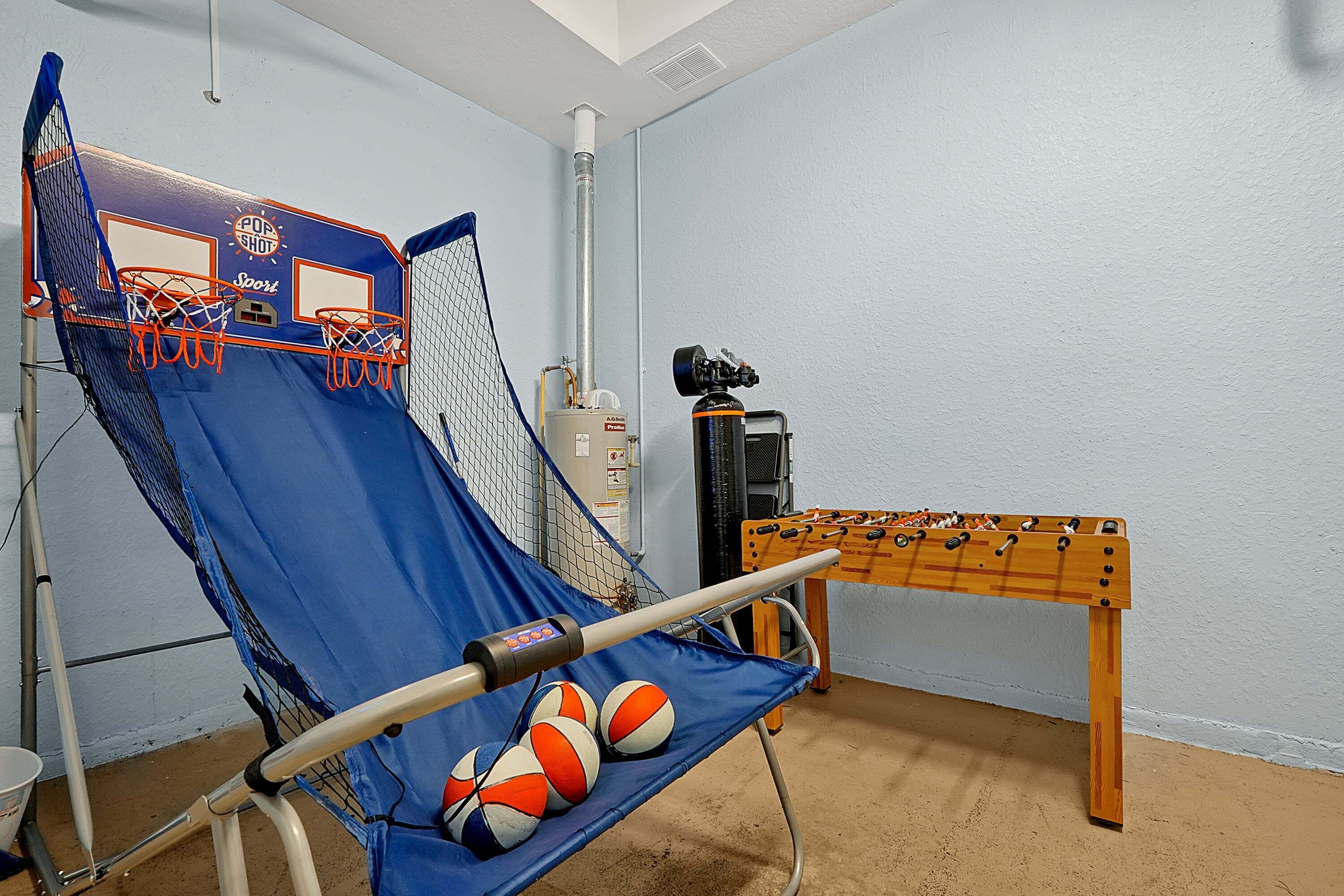 A room with a blue exercise ball, a foosball table, and a basketball hoop.