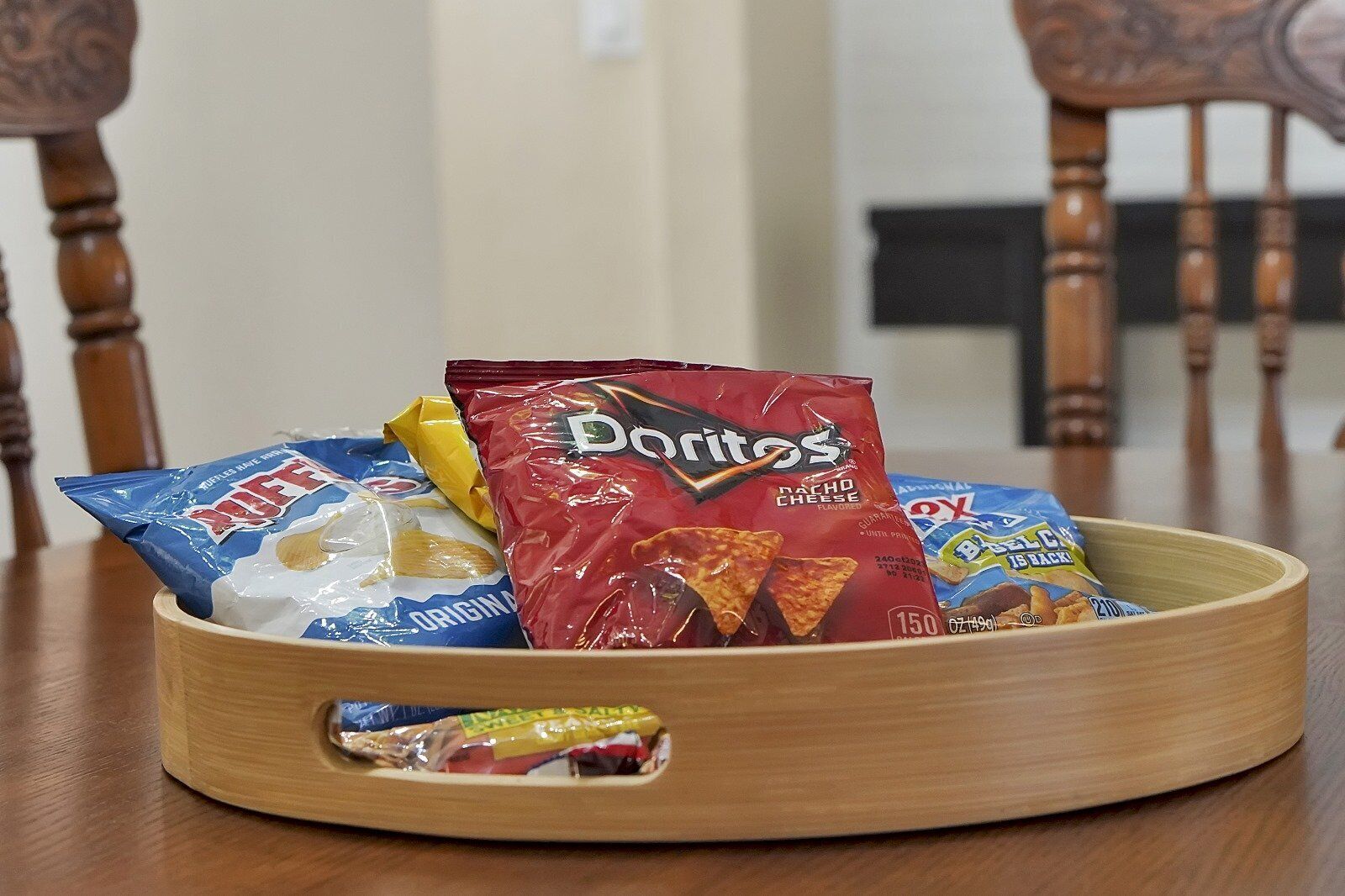 Un plateau en bois contenant divers sachets de collations, notamment des Doritos et d’autres en-cas.
