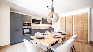 Una cocina moderna con armarios grises, una mesa de comedor de madera para seis comensales y una lámpara colgante.