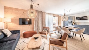 Una sala de estar moderna con un sofá, sillones, una mesa de centro y un televisor montado en la pared.