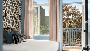 Quarto com uma cama grande, parede estampada e varanda com vista.