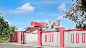 A gated entrance with a red and white wall, a sign for Graha Aisyah, and a clear blue sky. - Hotel O near Ring Road City Walks (Medan)
