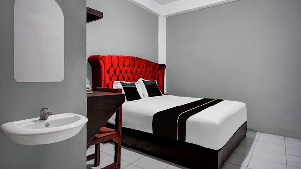 A bedroom with a white bed, red headboard, and a white sink. - Hotel O near Ring Road City Walks (Medan)