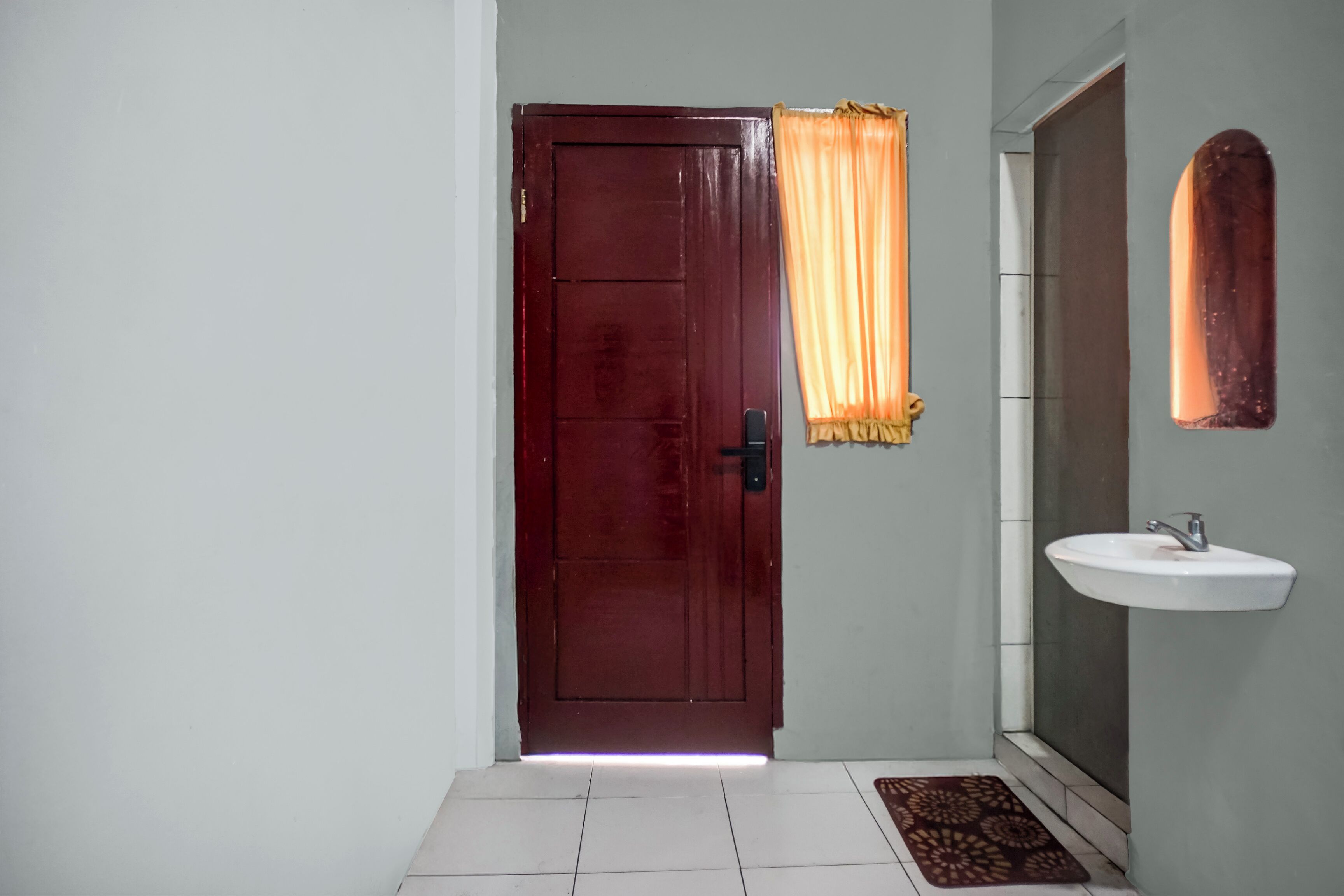 A bathroom with a wooden door, a white sink, and a patterned mat.