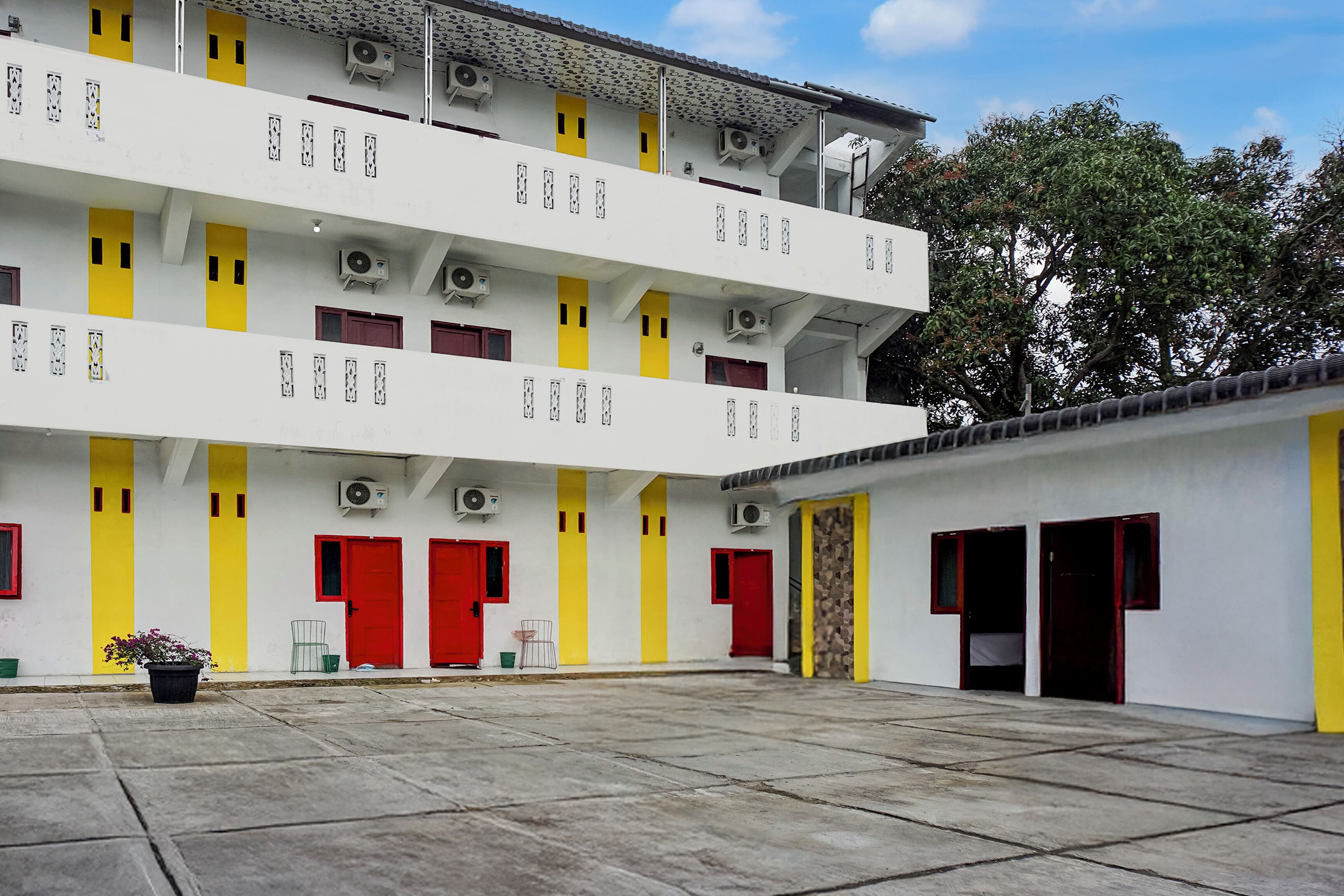 A multi-story building with yellow and red doors, air conditioning units, and a concrete courtyard.