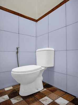 A bathroom with a white toilet, a shower, and a tiled floor. - Hotel O near Ring Road City Walks (Medan)