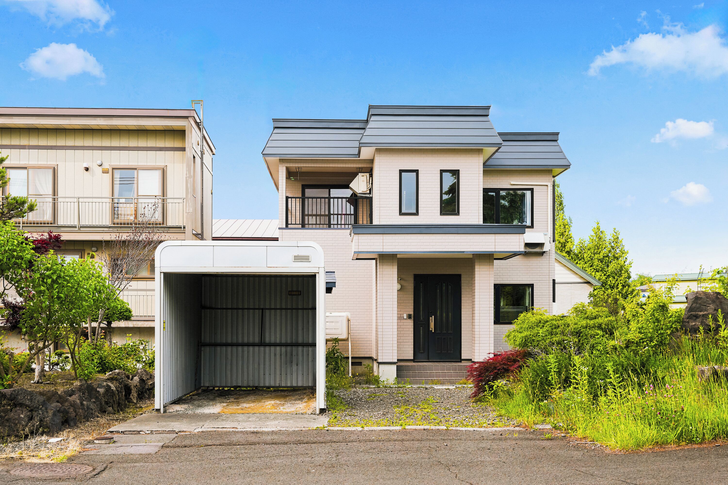 Un edificio residenziale a due piani con garage, un balcone e un'entrata principale.