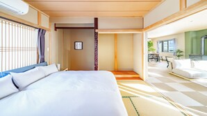 Une chambre d’hôtel avec un grand lit, un plafond en bois, une vue sur la salle à manger et une fenêtre avec des stores.