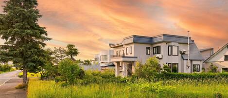 A modern two-story house with a flat roof, large windows, and a well-maintained lawn.