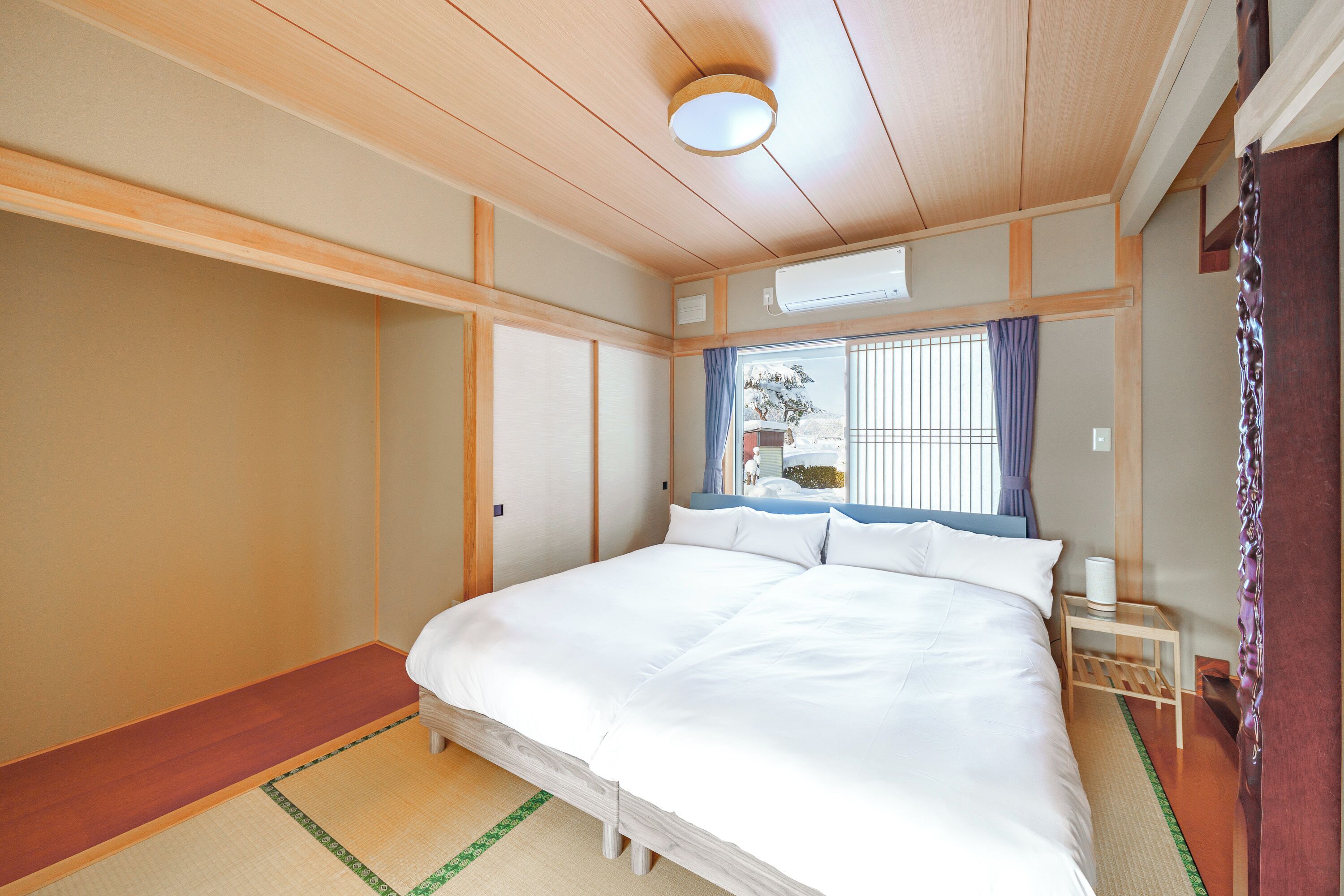 A hotel room with a large bed, wooden ceiling, and a window with curtains.
