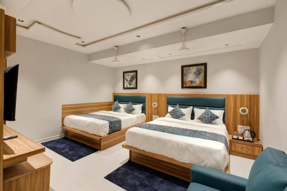 A hotel room with two beds, a desk, a chair, and artwork on the walls.