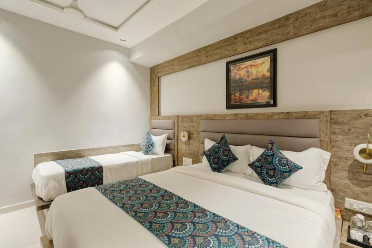 A hotel room with a large bed, a smaller bed, and a nightstand with a lamp.