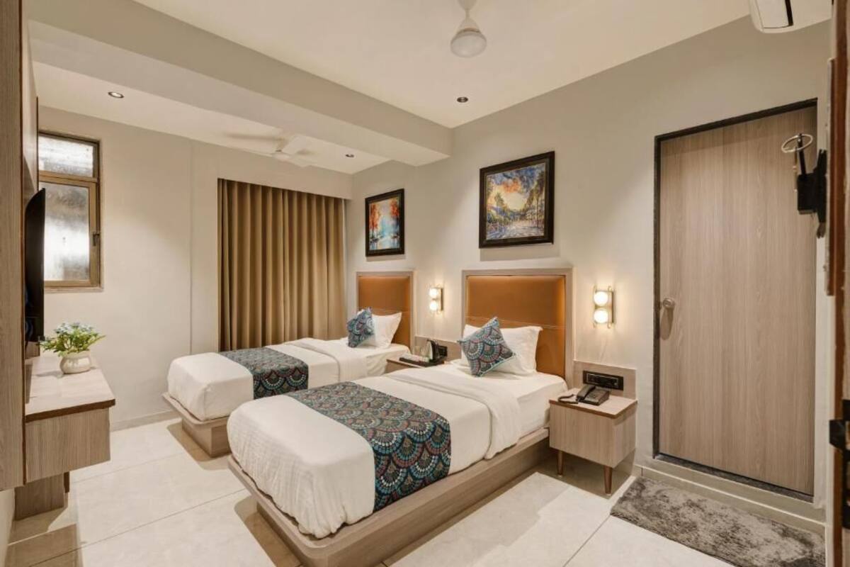 A hotel room with two beds, a desk, a chair, a wardrobe, and a bathroom.