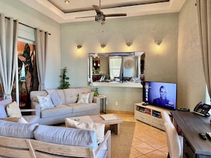 A living room with a sofa, coffee table, TV, and a ceiling fan.