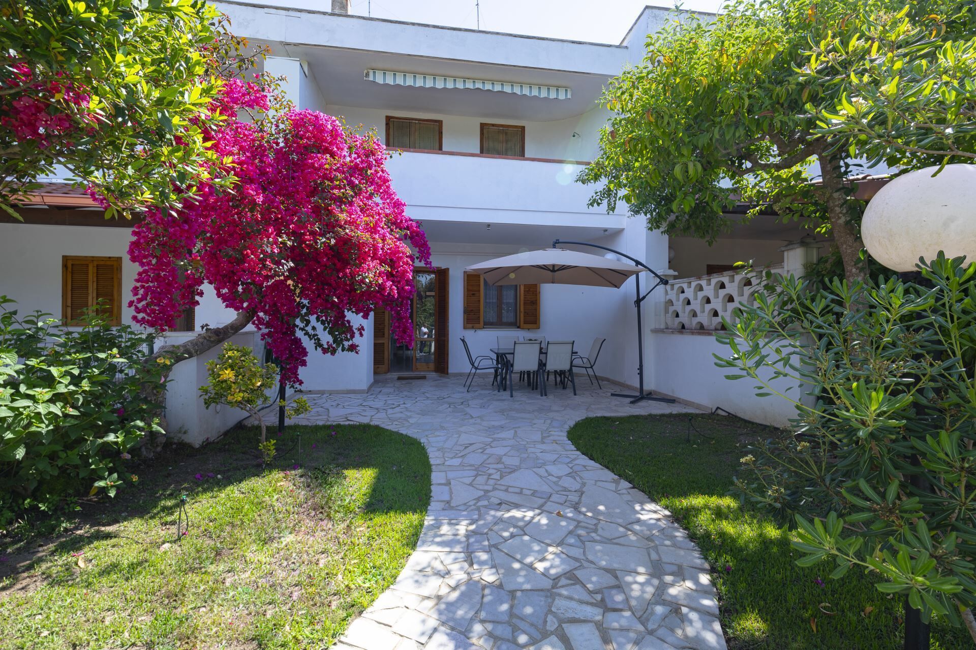 A courtyard with a stone pathway leading to a seating area with a table and chairs.
