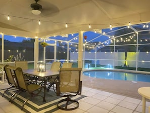 A covered outdoor area with a pool, string lights, and seating. - Spacious 4-bedroom house at Celebration, near Walt Disney World (Kissimmee)