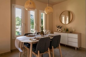 A dining area with a round table, chairs, a white cabinet, and a round mirror on the wall.